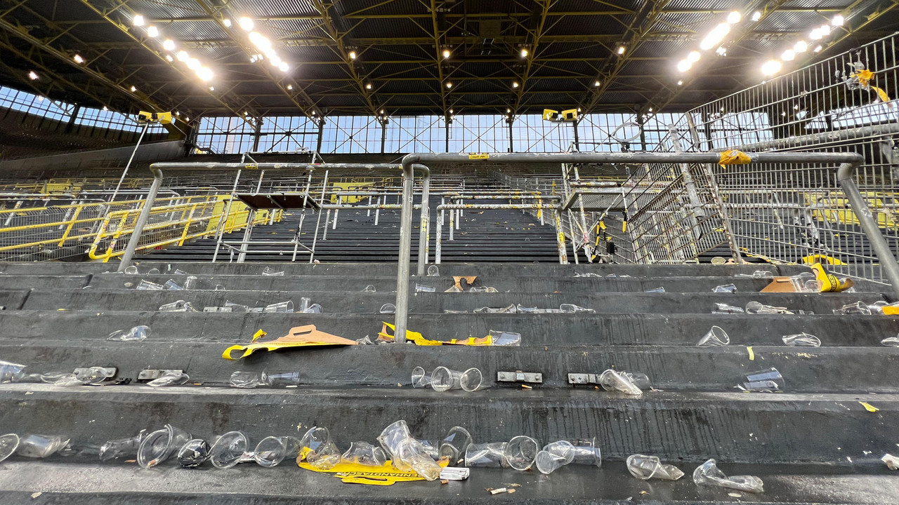 Leere Stadiontribüne mit vielen zurückgelassenen Plastikbechern und Müll auf den Stufen.