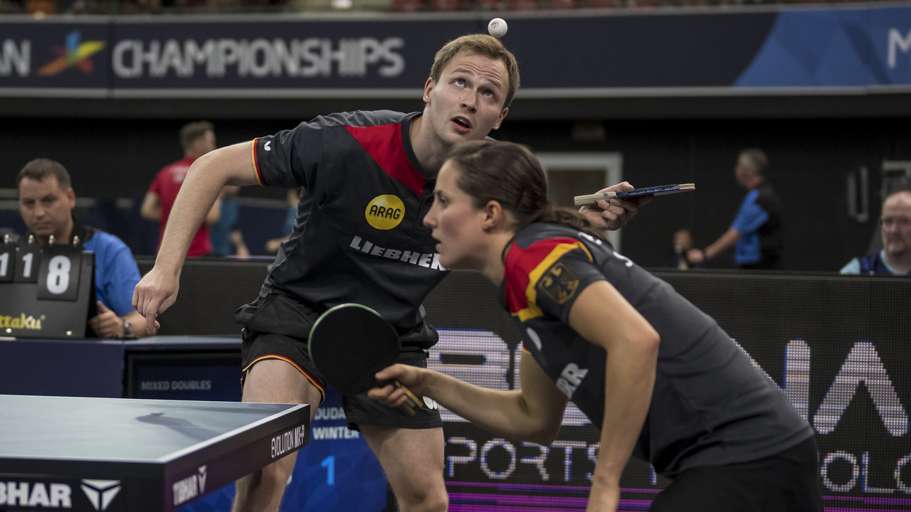 Zwei Tischtennisspieler im Doppel konzentrieren sich während eines Aufschlags.