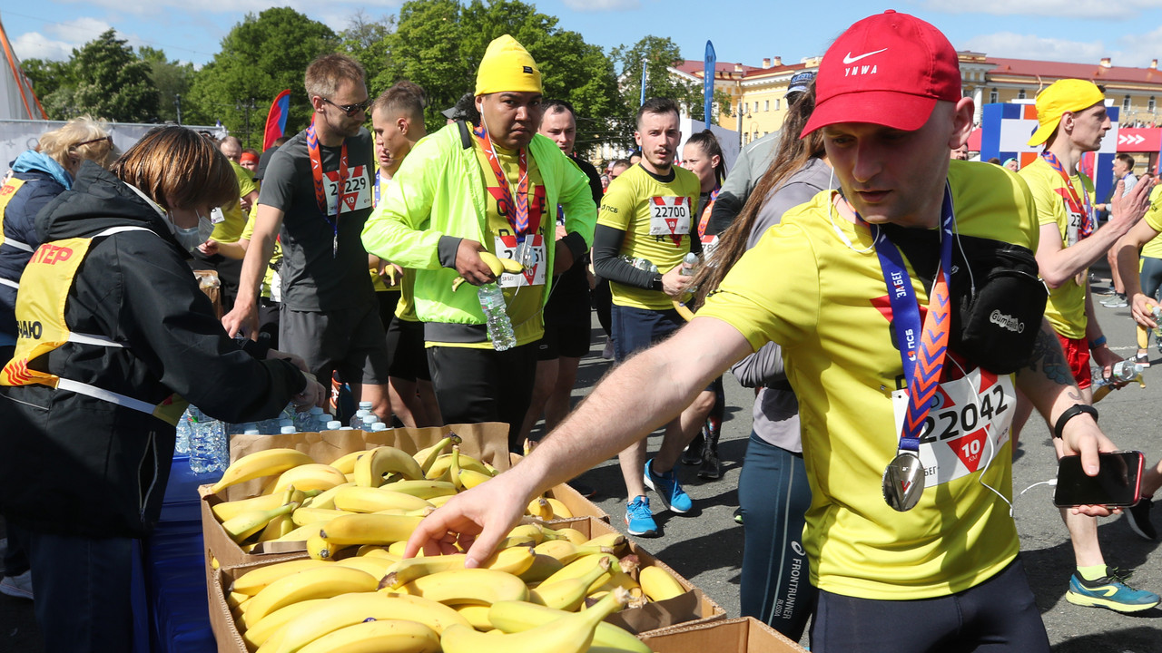 Marathonläufer greifen nach Bananen und Wasserflaschen an einer Verpflegungsstation.