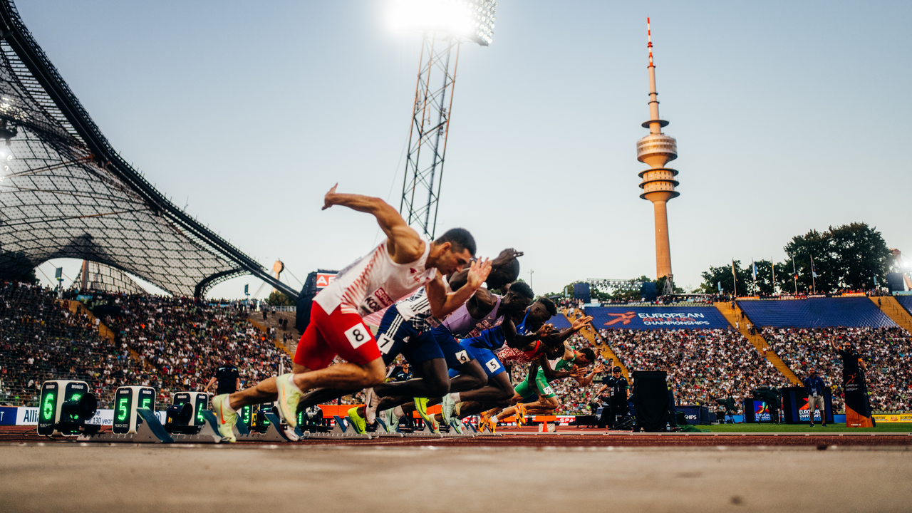 Sprinter starten gleichzeitig auf der Laufbahn im voll besetzten Stadion.