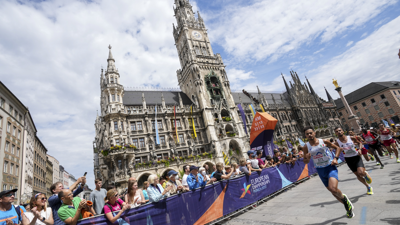 Marathonläufer passieren den Marienplatz in München während der European Championships 2022. Zahlreiche Zuschauerinnen und Zuschauer feuern die Athleten vor dem historischen Neuen Rathaus an.