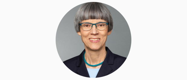 Porträt von Sylvia Schenk, die lächelt und eine Brille sowie eine blaue Halskette trägt.