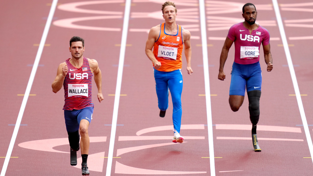 Drei Para-Leichtathleten mit Prothesen sprinten auf der Laufbahn bei einem Wettkampf.